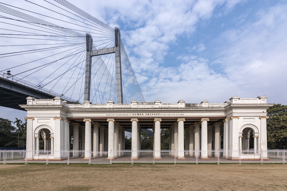 a large white building with pillars and a bridge in the background