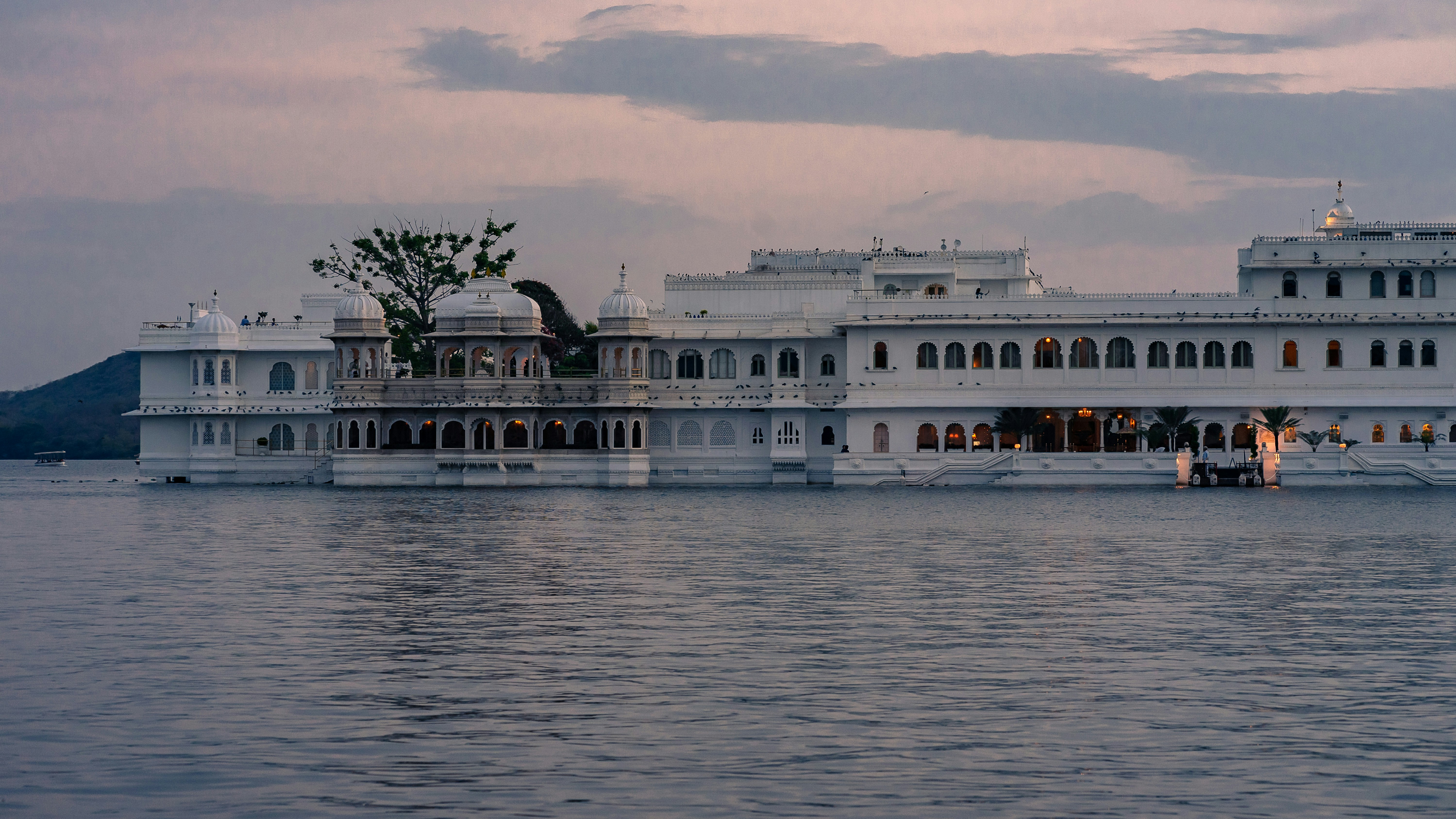 a large white building sitting on top of a body of water, Palace on water during evening