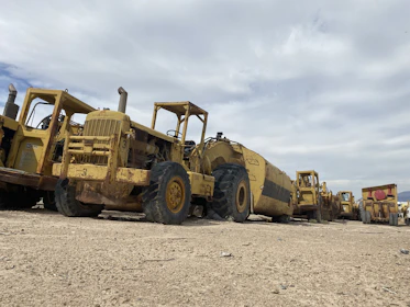 Rows of heavy equipment lined up on a dusty yard, ready to roll out.