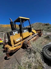 A sturdy bulldozer ready for earthmoving work on a rural terrain.