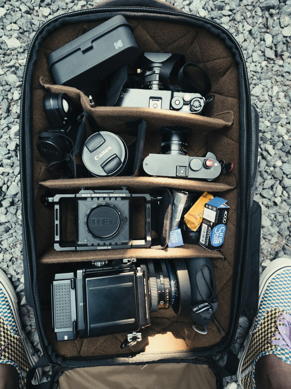 une personne debout devant un sac à dos rempli de caméras