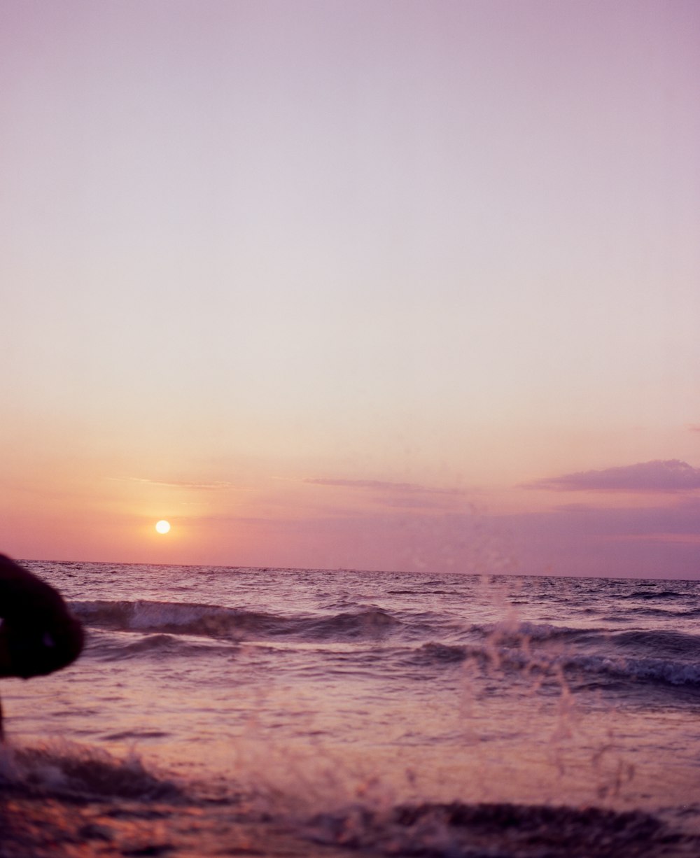 a person standing on a beach with a surfboard