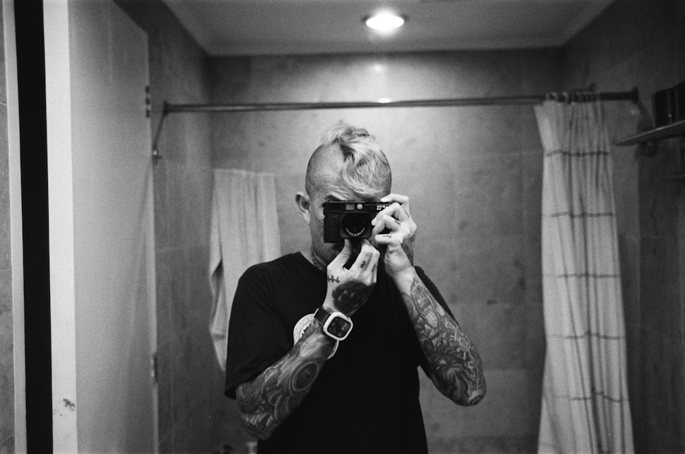 バスルームの鏡で自分の写真を撮る男性