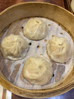 Delicate dumplings served on a bamboo steamer with a sprinkle of sesame seeds.