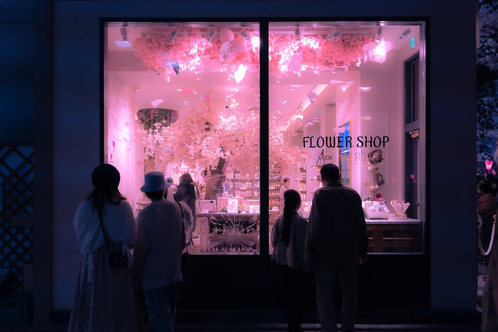 a group of people standing in front of a flower shop