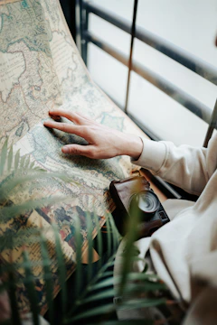 Close-up of hands holding a vintage map with delicate travel notes.