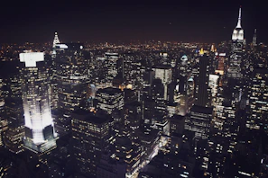 A nighttime view of a busy financial district with illuminated skyscrapers.