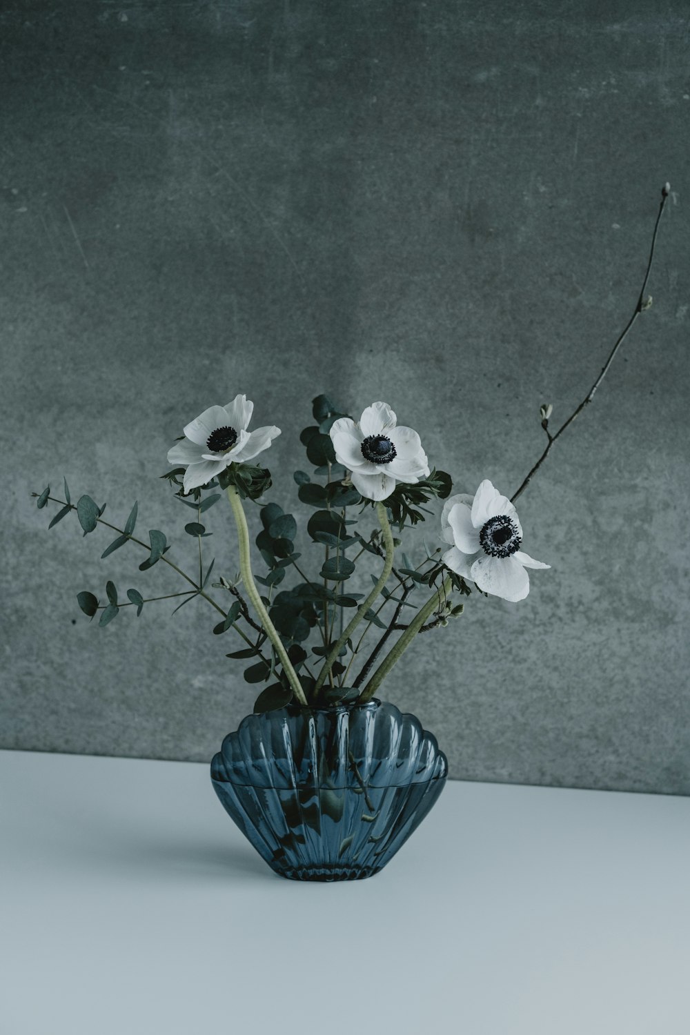 a blue vase filled with white flowers on top of a table