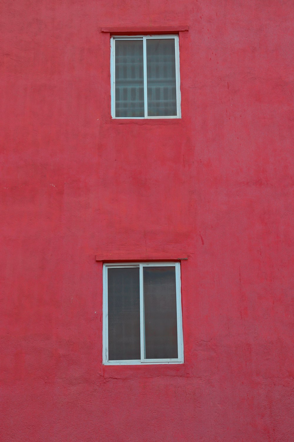 a red building with two windows and a clock