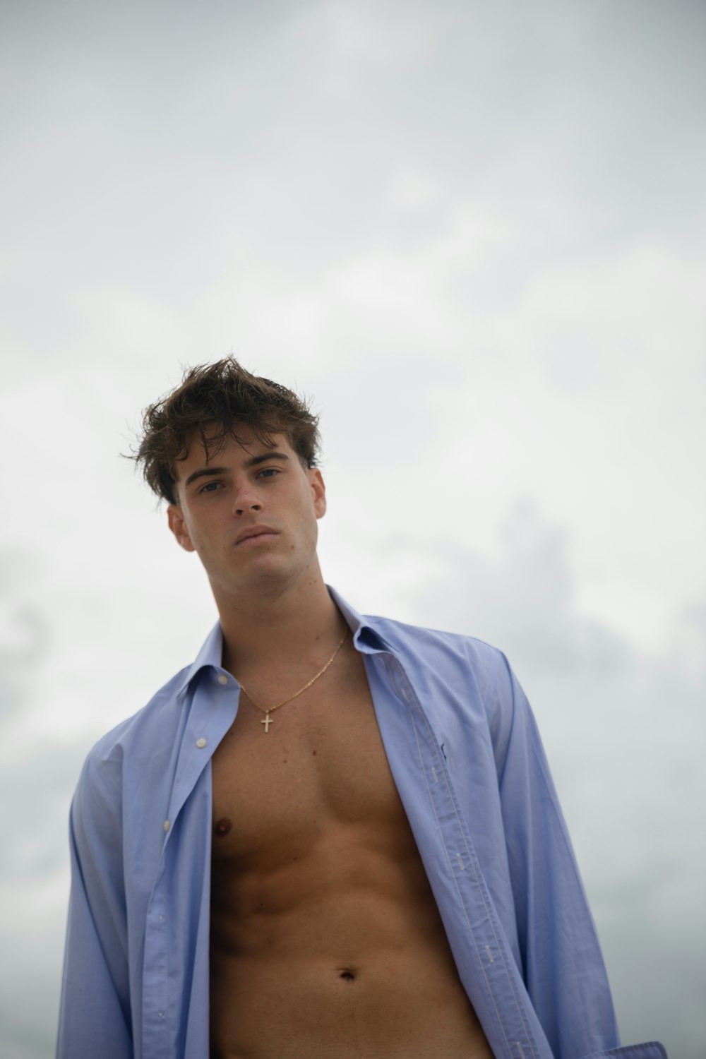 a man with no shirt standing in front of a cloudy sky