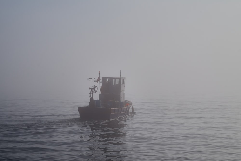 a boat in the middle of the ocean on a foggy day