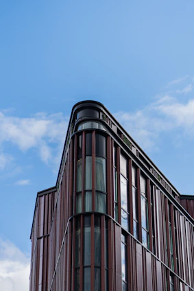 A sleek modern commercial building with geometric patterns and warm brown tones under a clear sky.