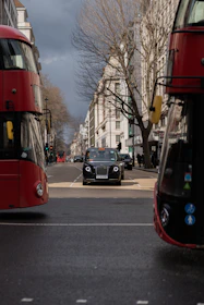 A Swiftfare taxi driving smoothly along a city street with iconic UK landmarks in the background.