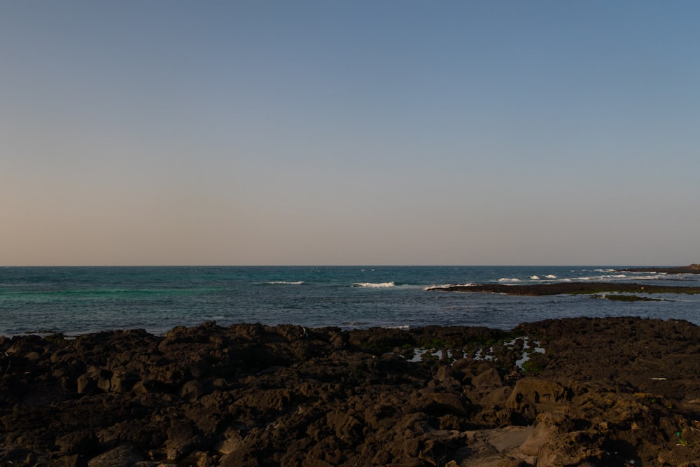 a large body of water sitting next to a rocky shore