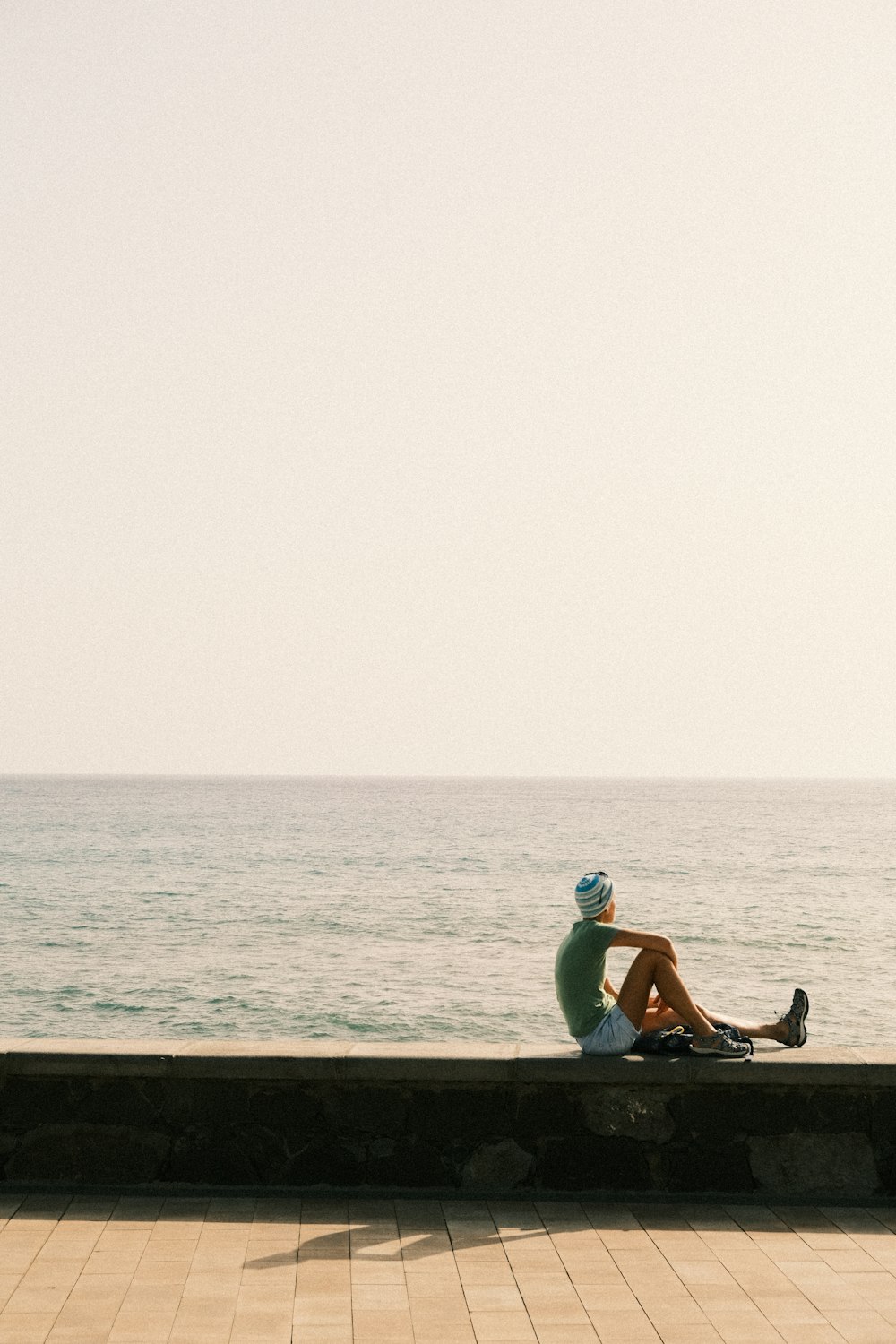 a person sitting on a wall near the ocean