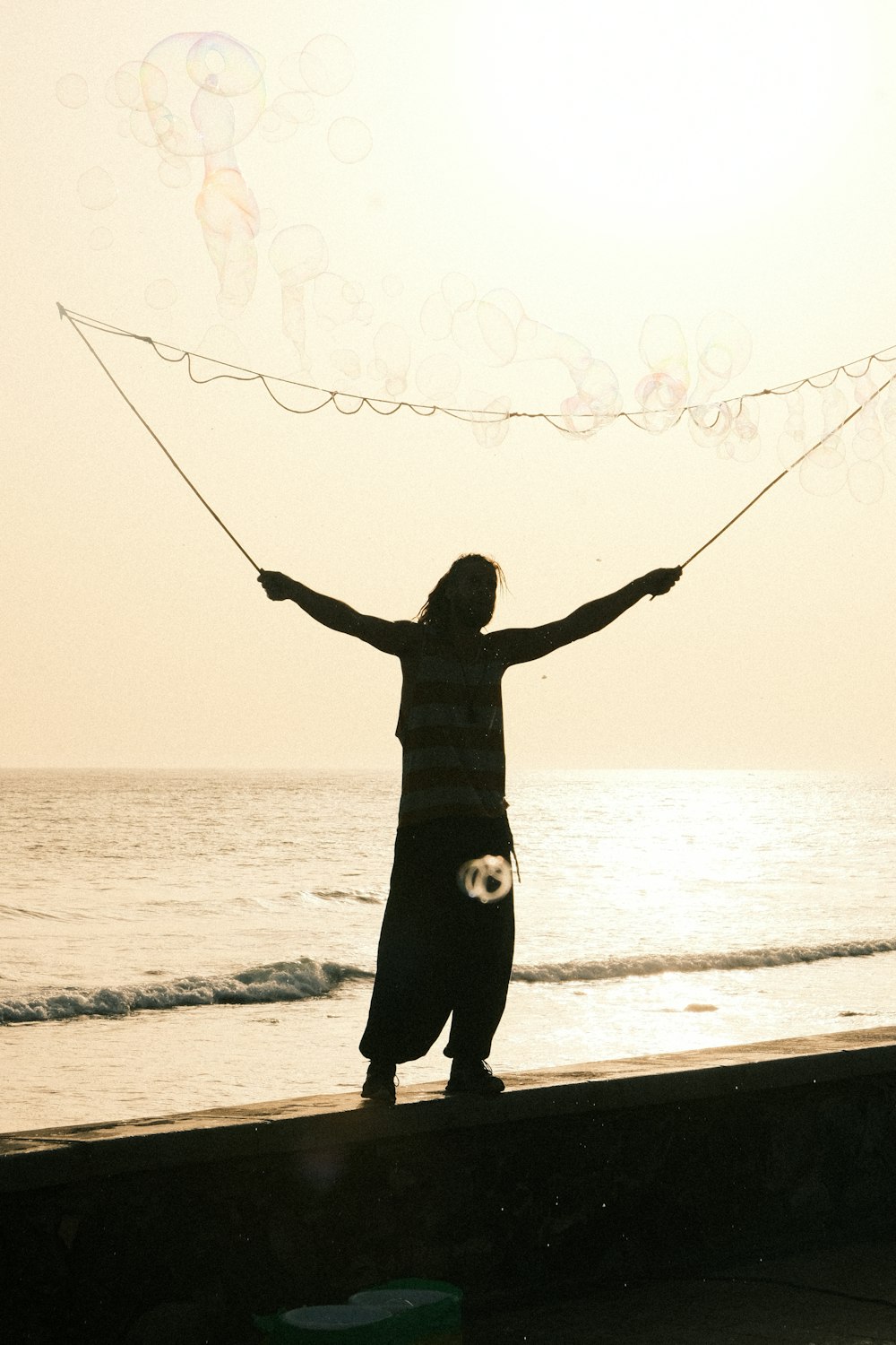 a woman standing on a beach holding a kite