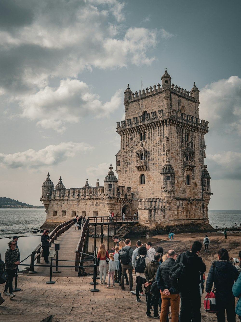 a group of people standing around a castle by the water