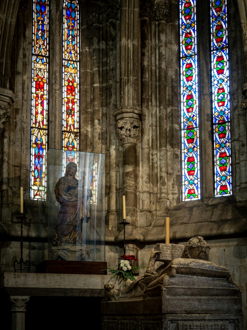 a statue in front of a stained glass window