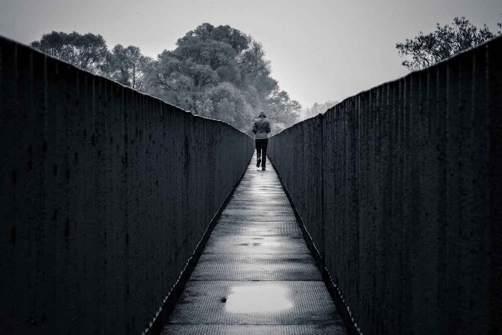 a person walking across a bridge in the rain