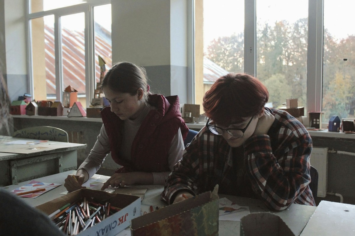 A group of scout troop volunteers sitting at a table, organizing schedules and sign-ups for upcoming events and activities.