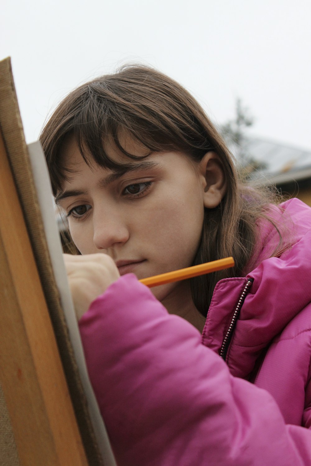 a girl in a pink jacket is holding a pencil