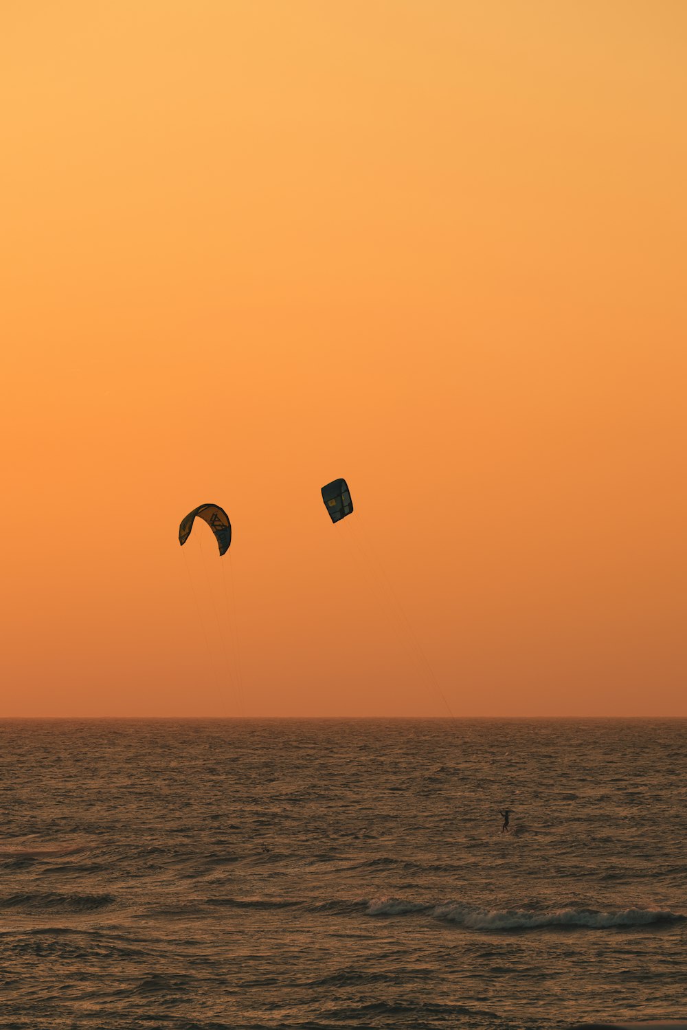 Un par de cometas volando sobre el océano al atardecer