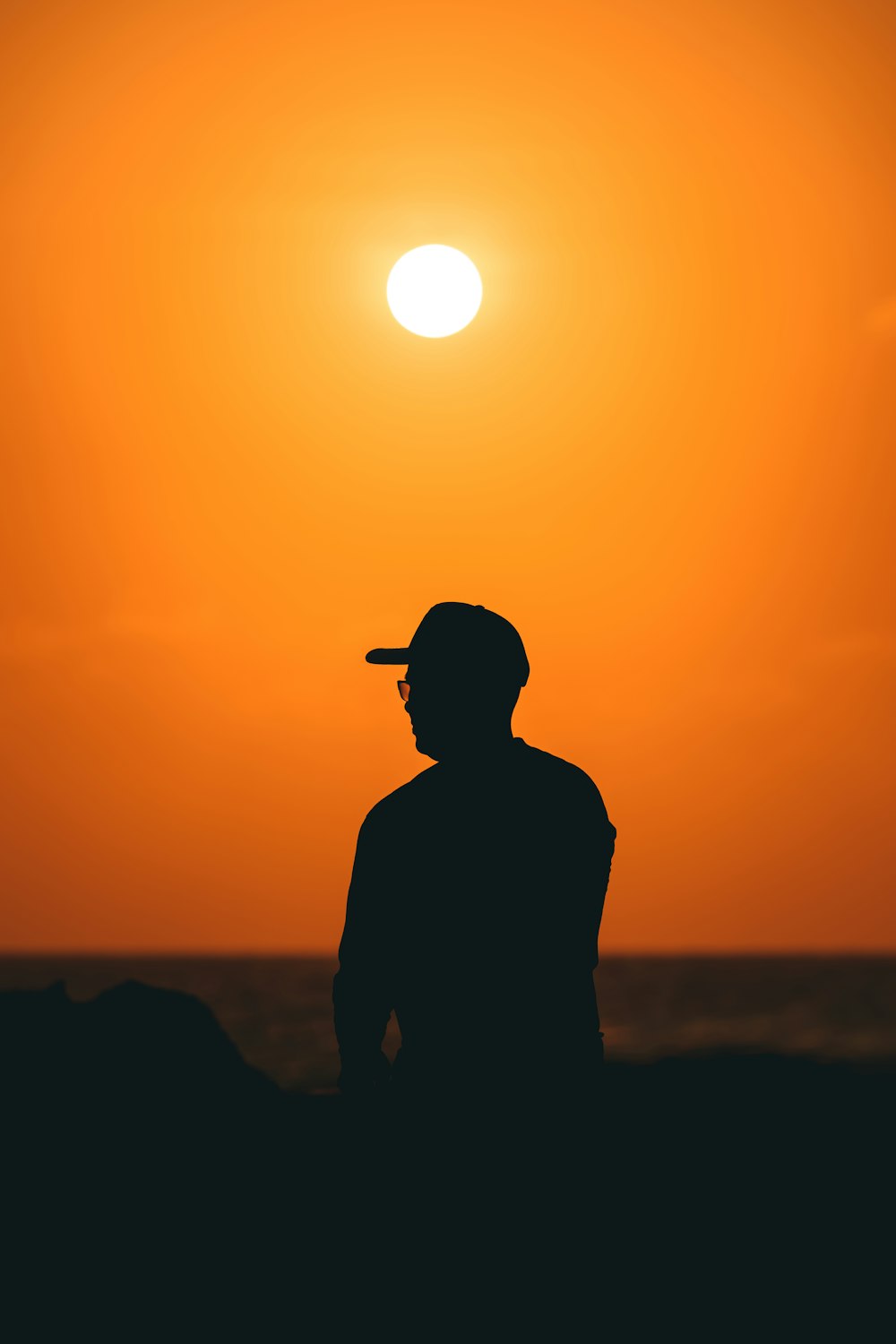 a person standing on a beach with the sun in the background