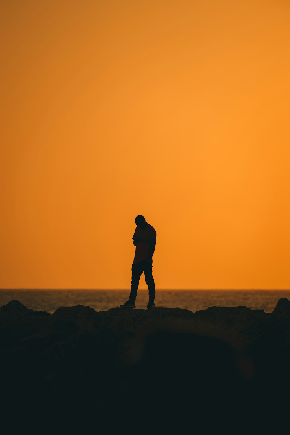 a man standing on top of a rock next to the ocean