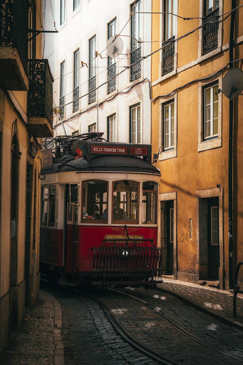 Ein roter Straßenbahnwagen fährt eine Straße neben hohen Gebäuden entlang