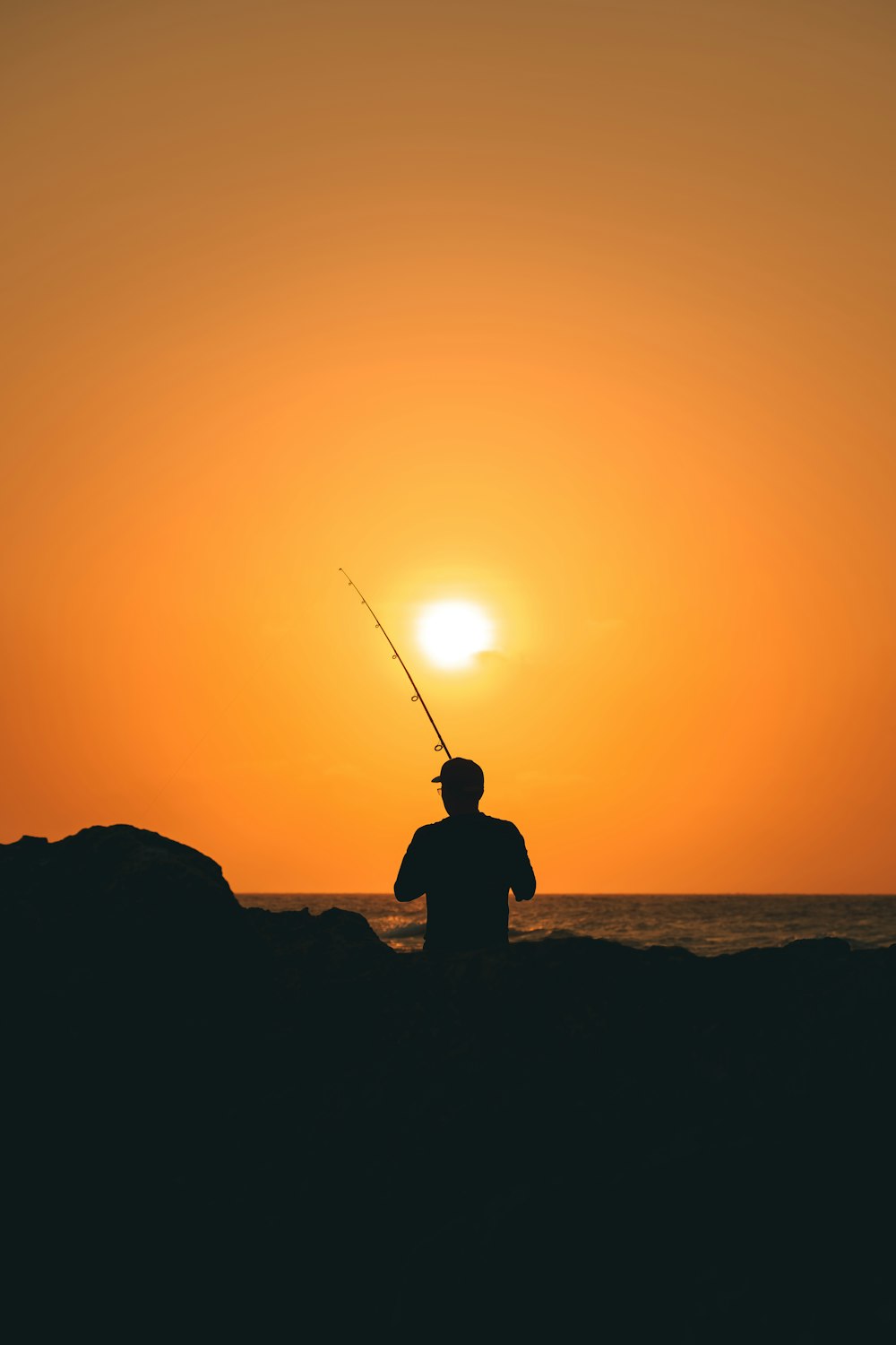 a silhouette of a man fishing at sunset