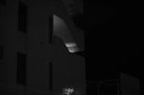 A large, moody black-and-white cinematic shot of a modern architectural structure at dusk.