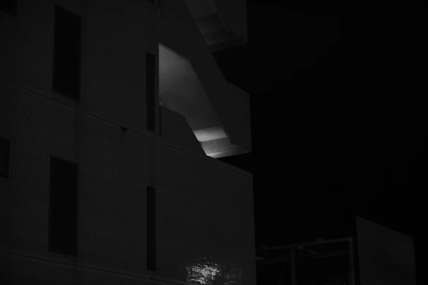 A moody black-and-white photograph capturing the shadows and shapes of a theatrical set design.