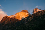 Golden sunrise casting warm light over a rugged mountain ridge.