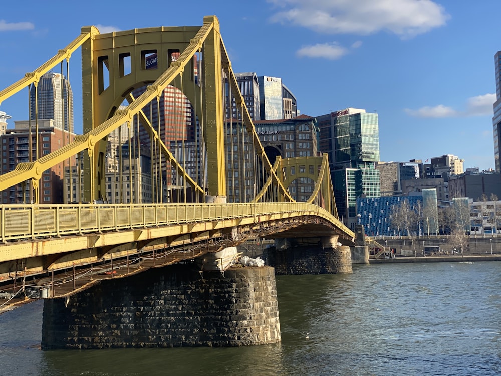 a yellow bridge over a body of water with a city in the background