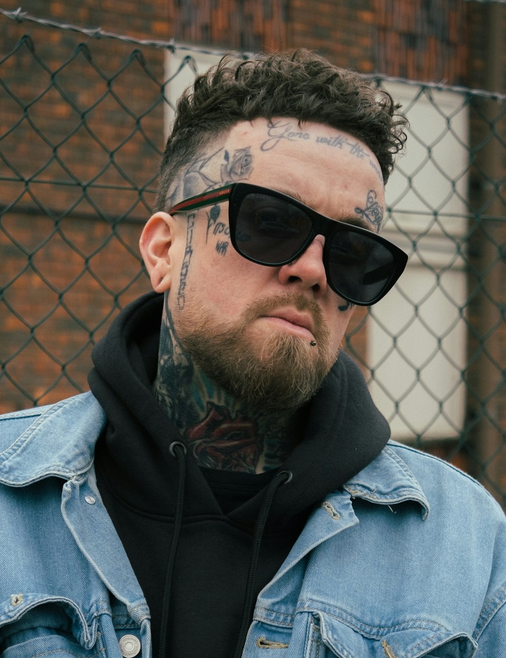 a man with a tattoo on his face wearing sunglasses
