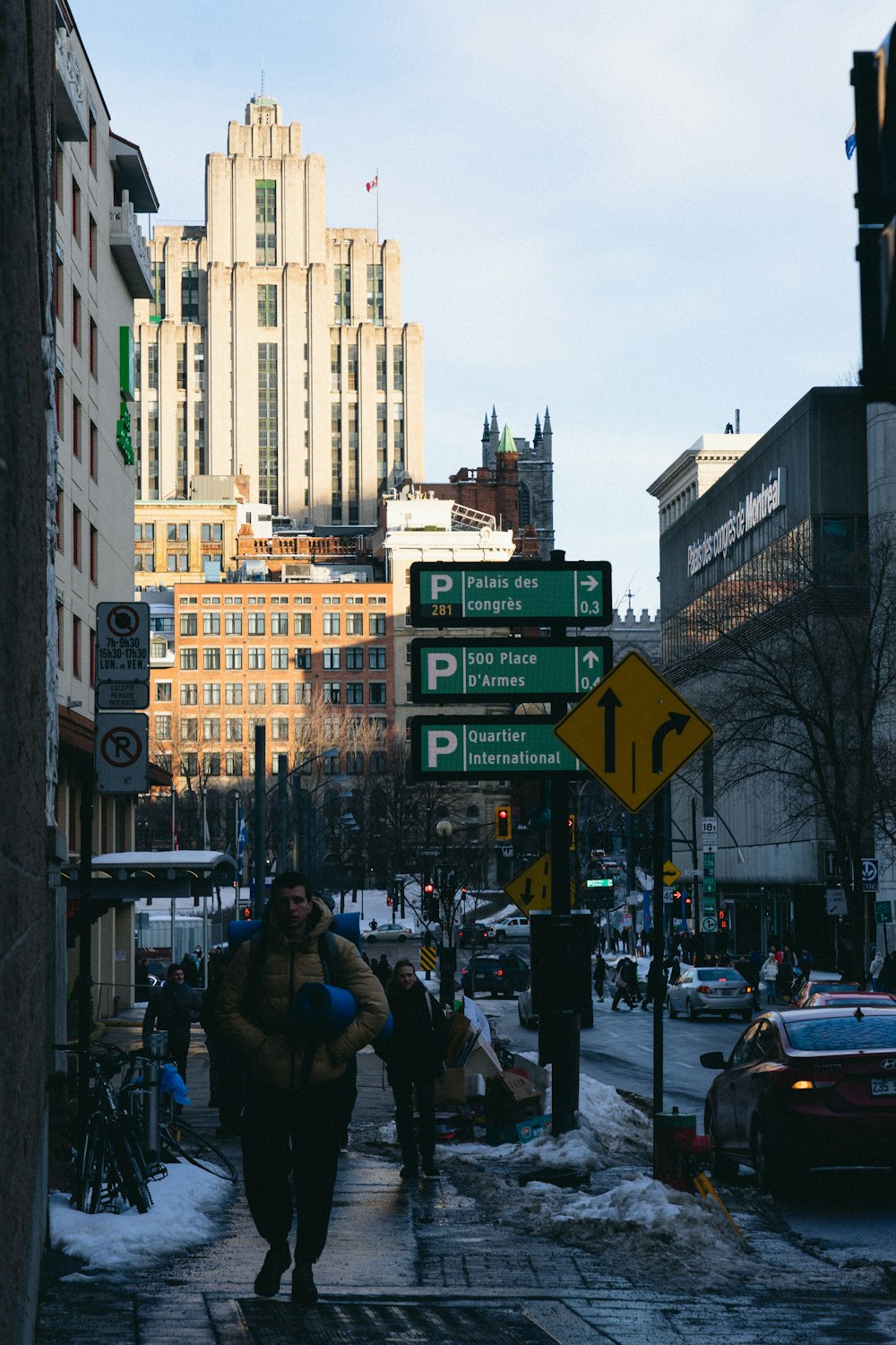 a couple of people walking down a street next to tall buildings