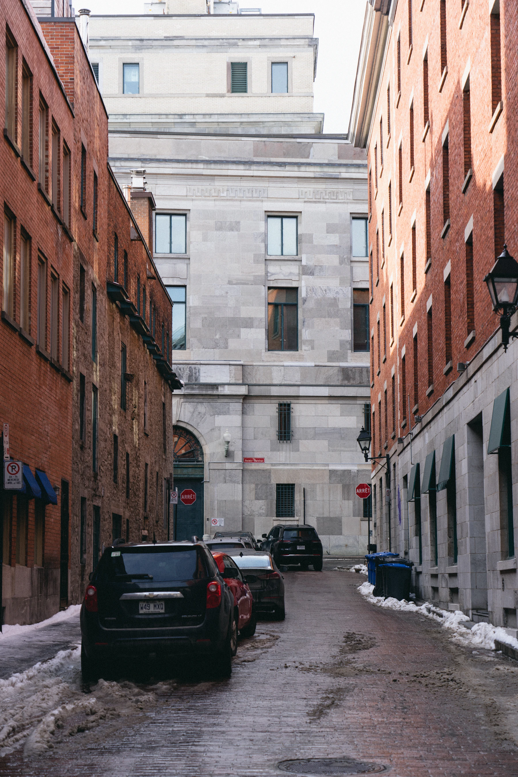 Cars are parked on a narrow Canadian city street.