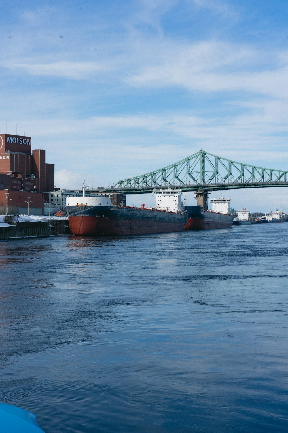 a large cargo ship in the water near a bridge