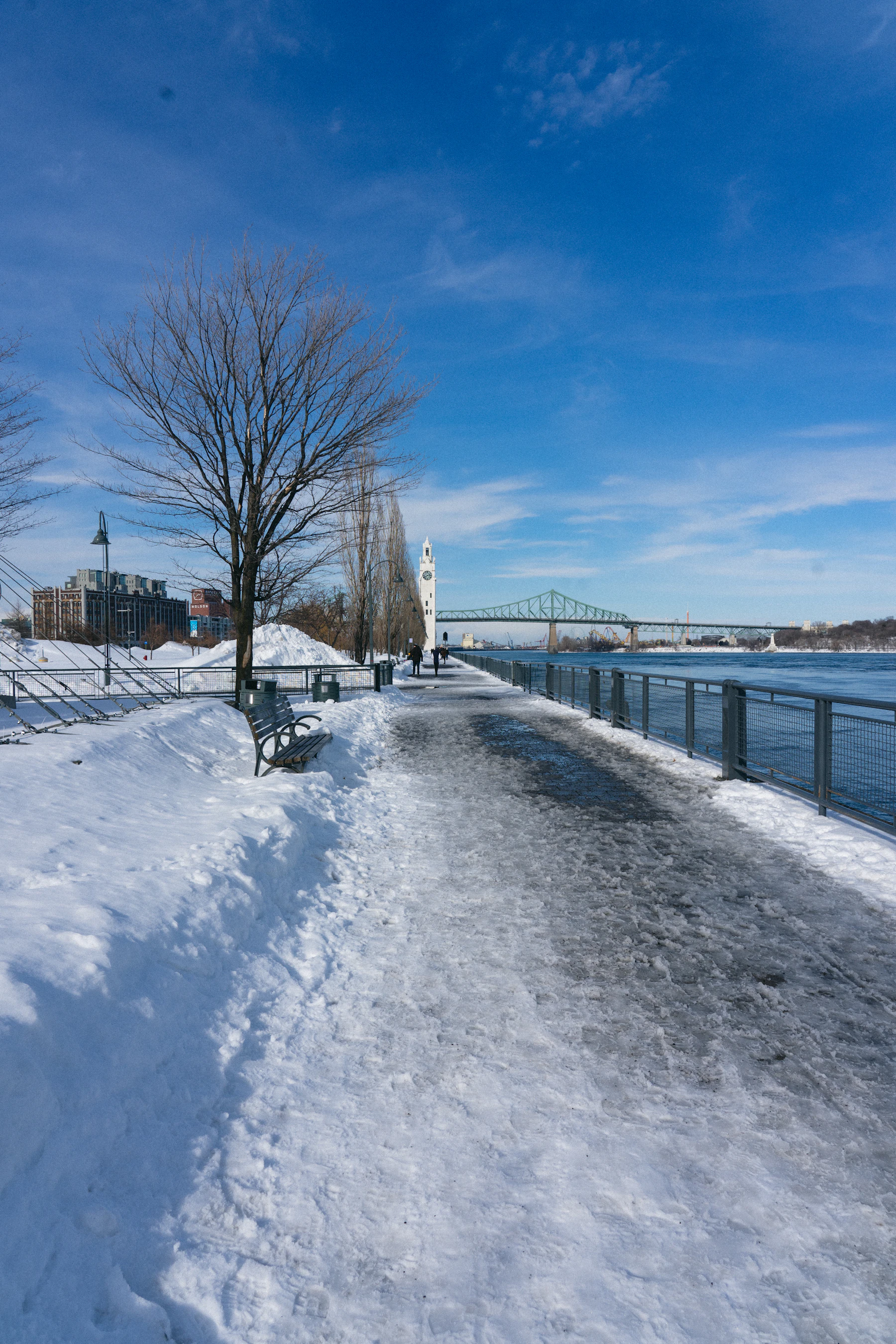 A snow-covered bench faces water in Canada.
