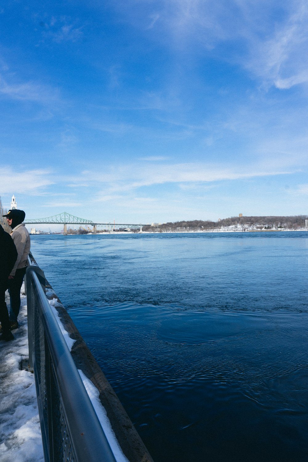 a couple of people standing next to a body of water