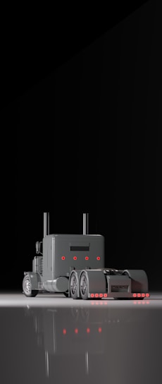 A sleek black and gold semi-truck cruising down an open highway at sunset, embodying strength and reliability.