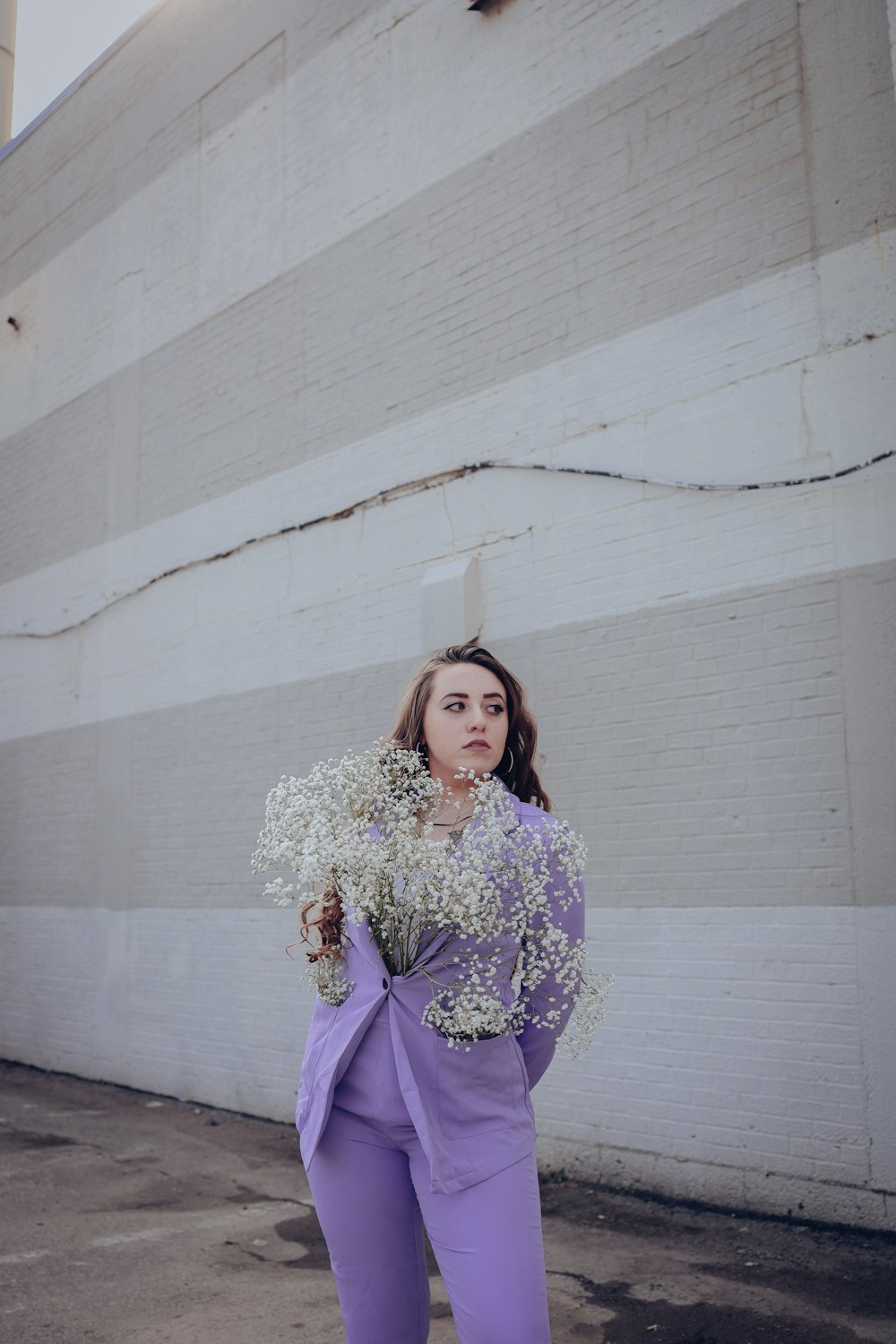 a woman holding a bunch of flowers in front of a building