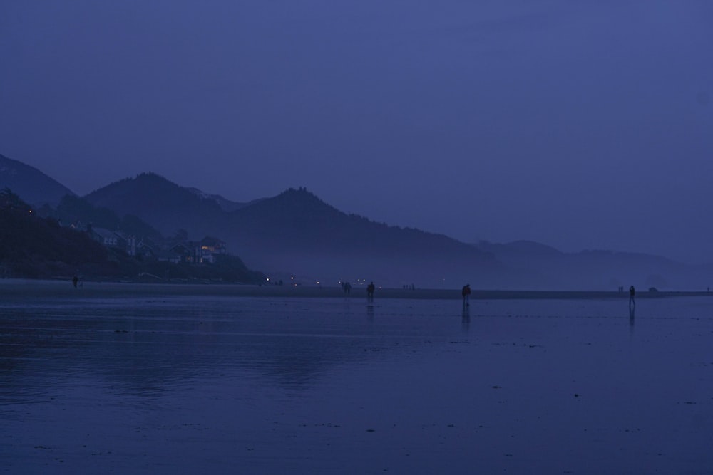 a group of people standing on a beach at night