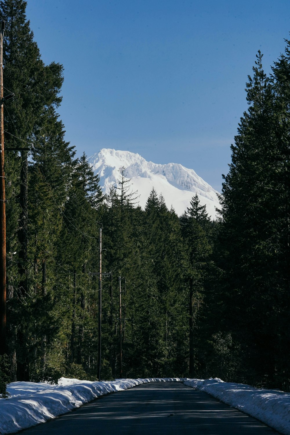 a road with snow on the ground and a mountain in the background