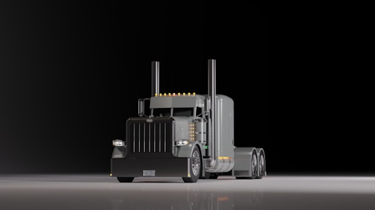 A large, shiny semi-truck with a prominent front grille is positioned on a reflective surface against a dark background. The truck features dual exhaust stacks and a sleeper cab design with several orange lights along the roofline.