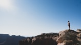 A lone traveler standing on a rocky cliff overlooking a sunrise-lit valley