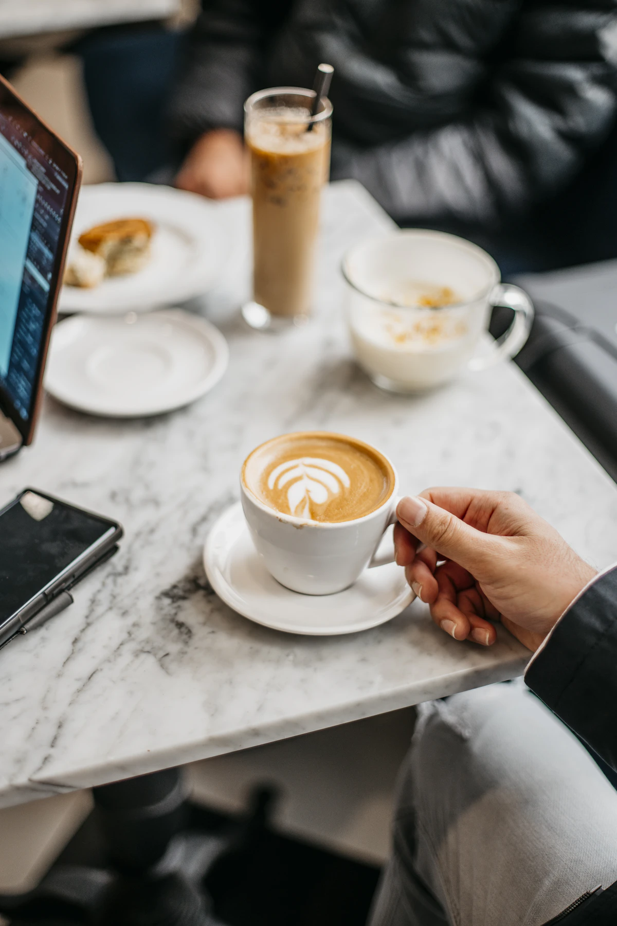 A person at a table with a laptop and a coffee