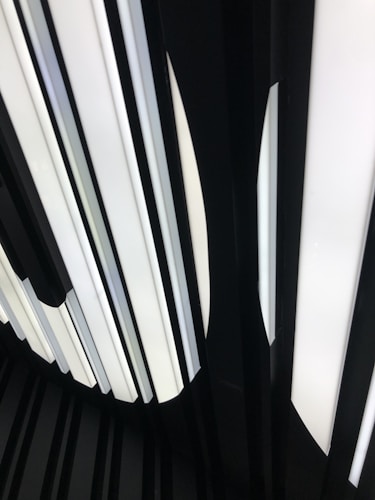 Vertical illuminated panels with alternating black and white elements create a modern, abstract pattern. The lighting suggests a futuristic or minimalist design.