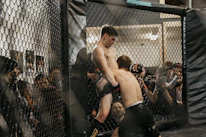 Close-up of two athletes engaging in a clinch hold during an MMA training session.