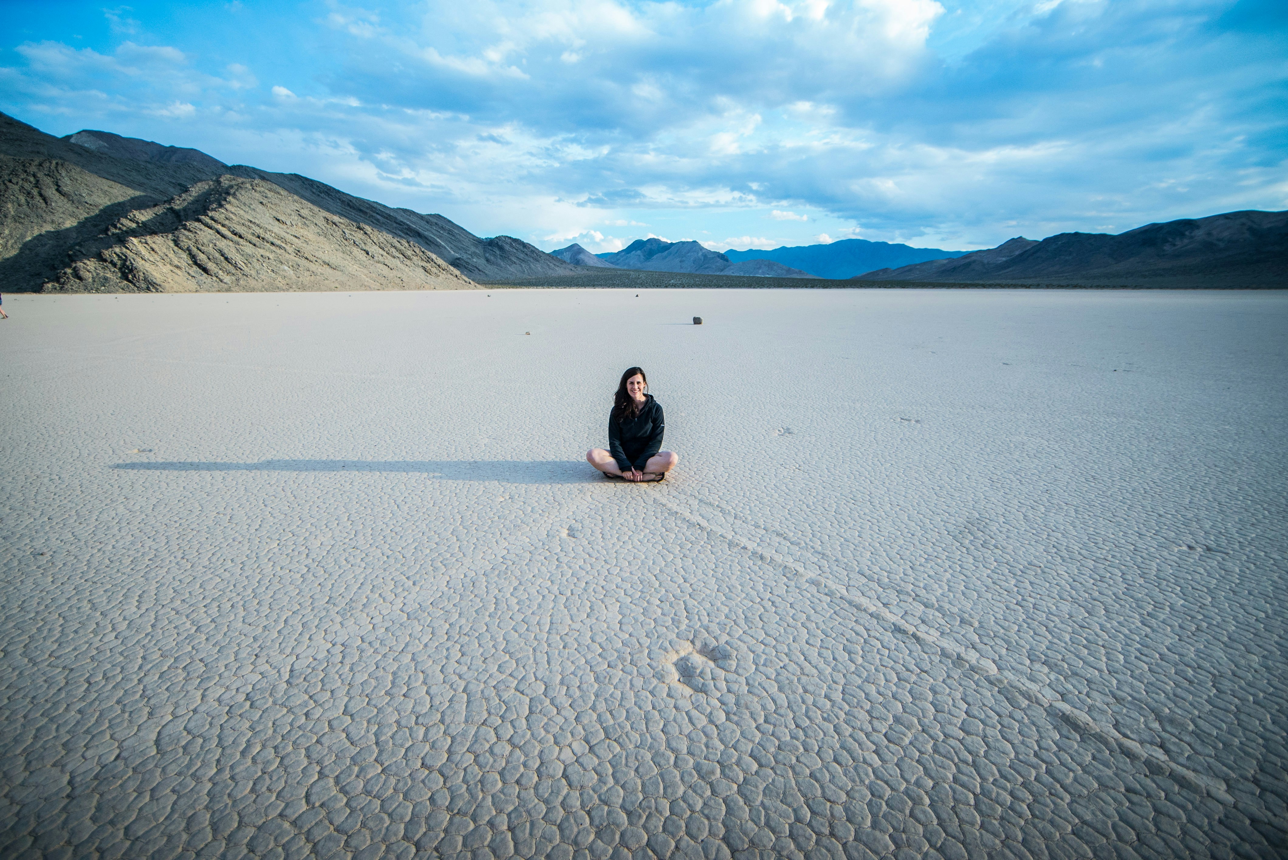 a woman sitting in the middle of a desert